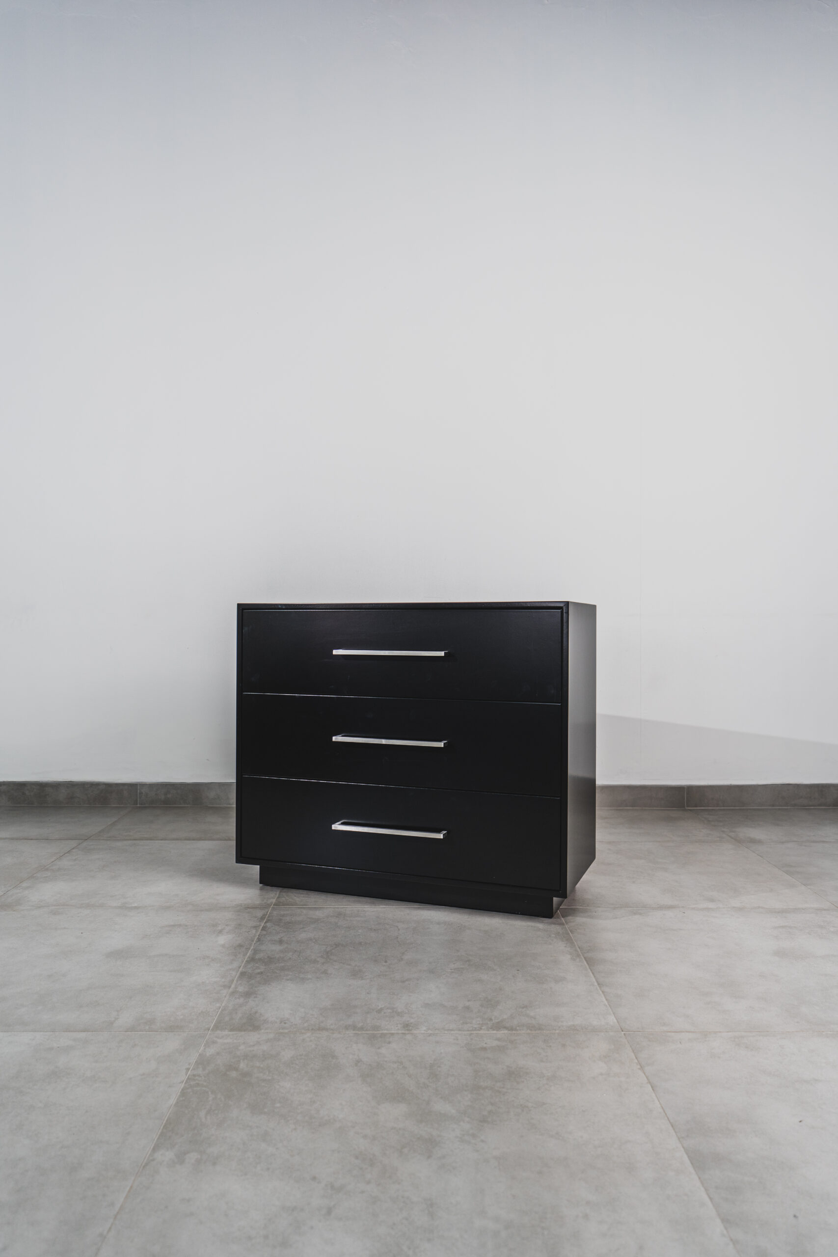 Black 3-drawer chest of drawers with silver handles, modern bedroom storage unit.