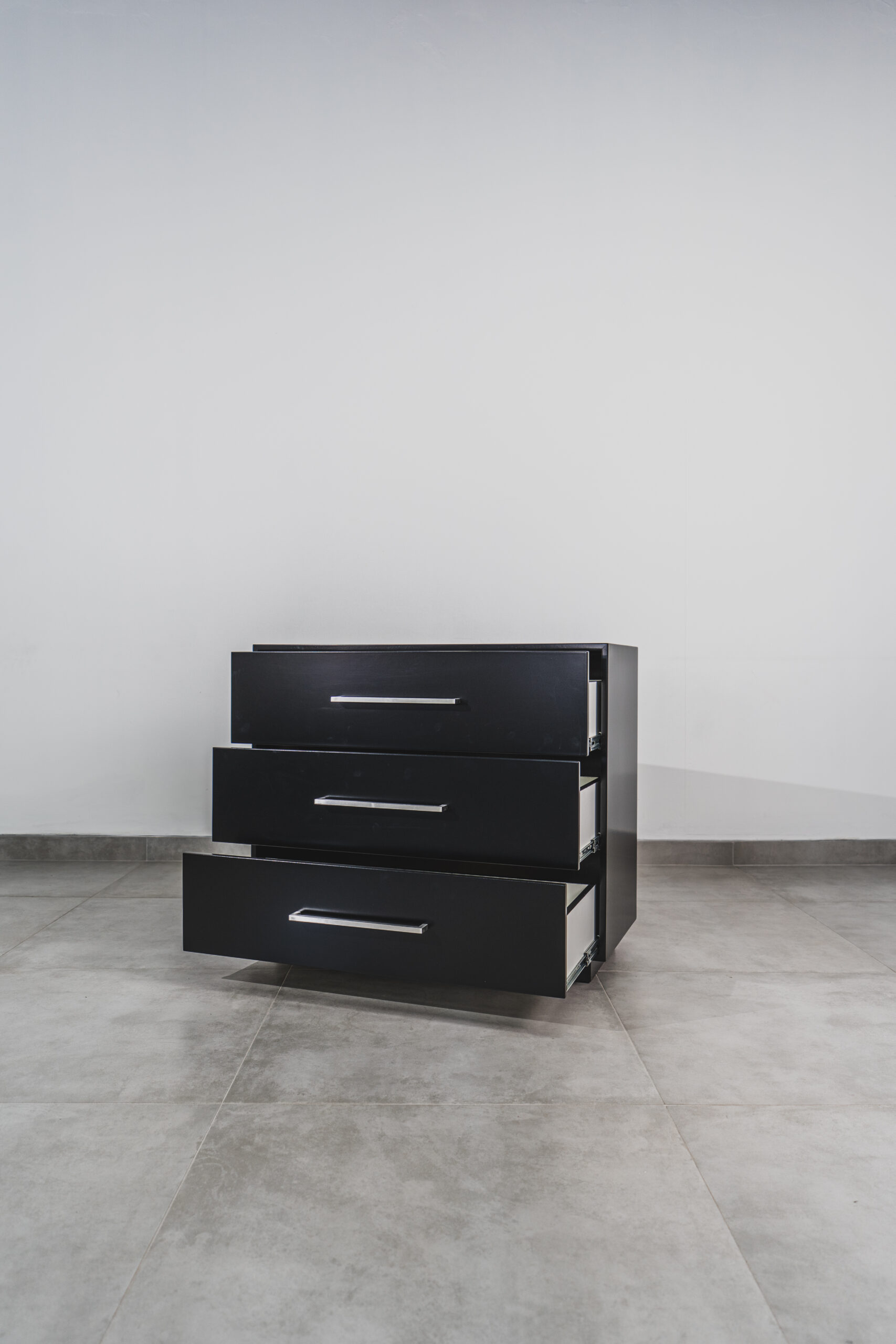 Black 3-drawer chest of drawers with silver handles, shown with drawers open for storage display.