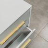 Top view of a white bedside table with two drawers slightly open, featuring sleek gold handles and a modern minimalist design.