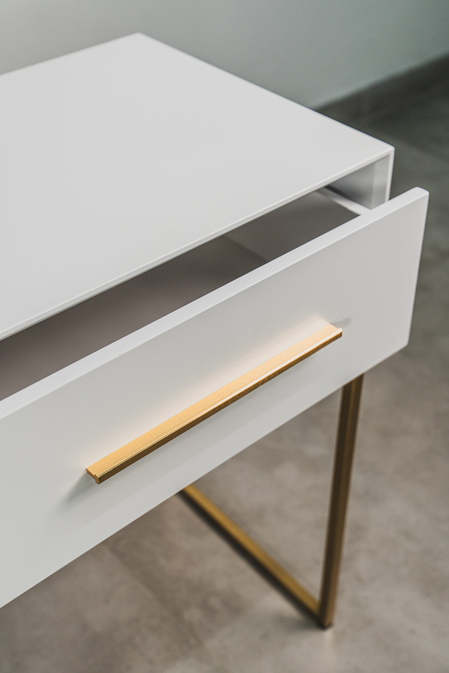 White and gold dressing table drawer close-up, featuring gold handle detail and modern bedroom furniture design.