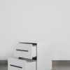 Modern white two-tone side table with black handles and steel base, featuring two open drawers and a sleek minimalist design.