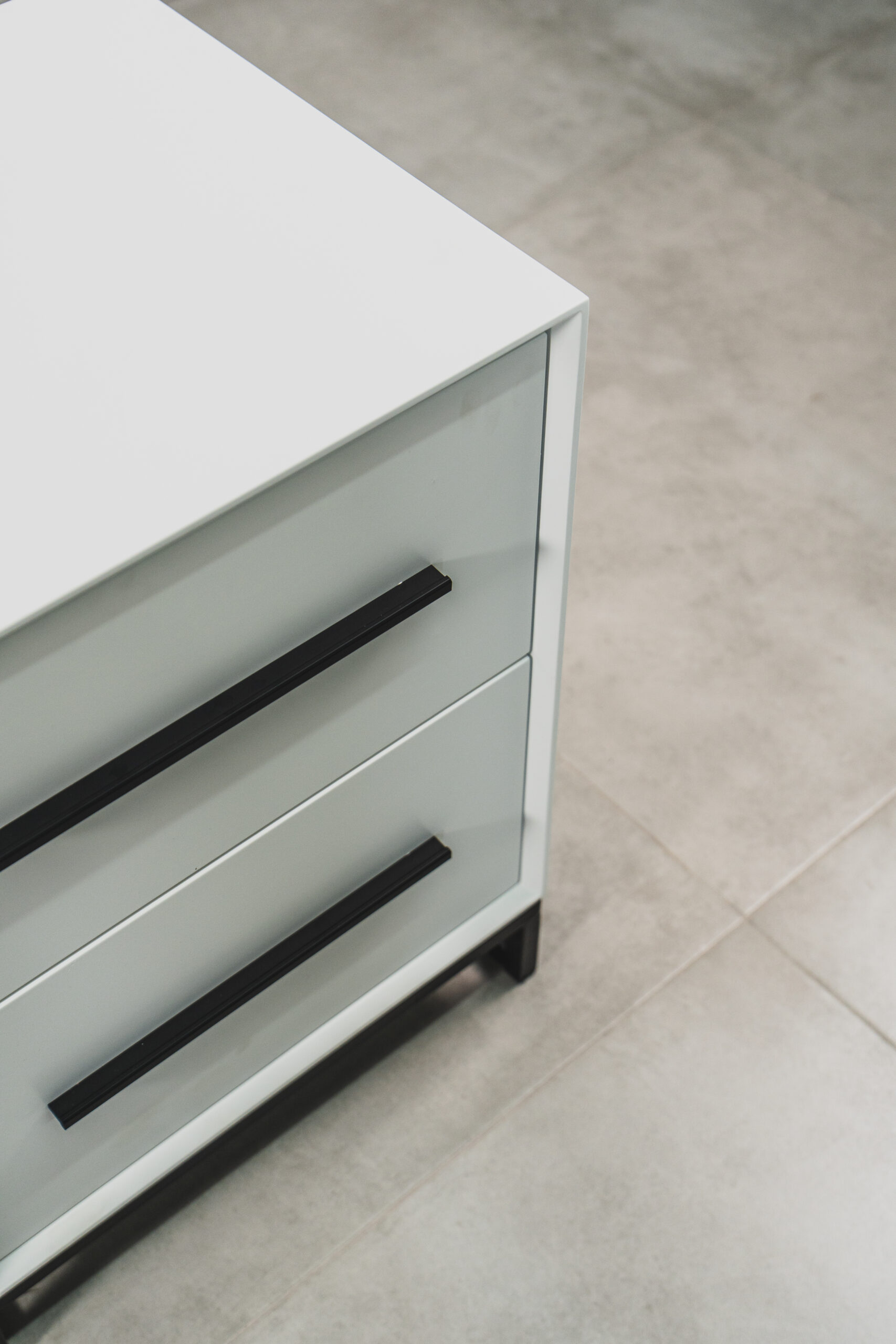 Close-up of a modern white two-tone side table with black handles and a black steel base, highlighting its sleek minimalist finish.