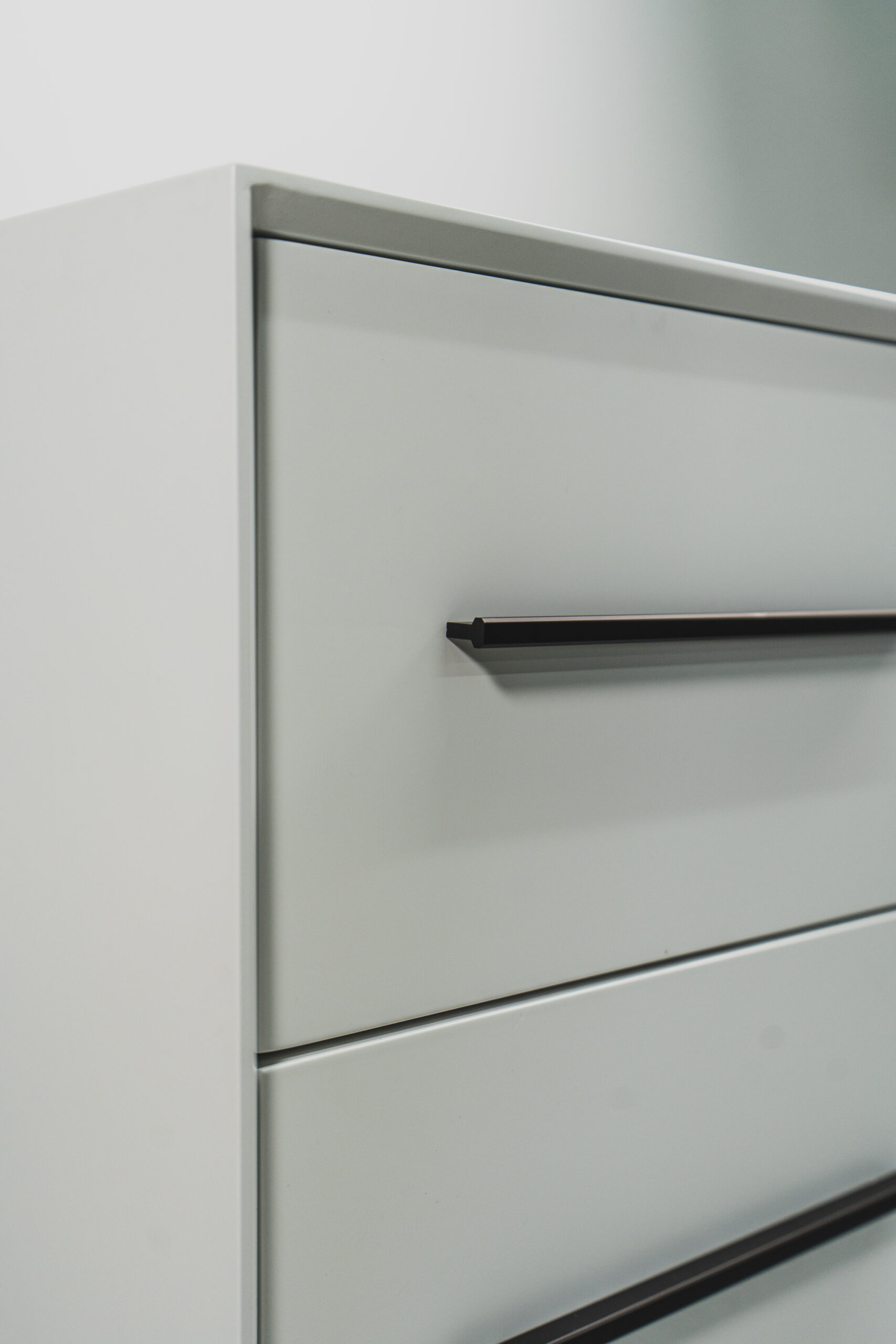 Close-up of a white modern side table featuring sleek black handles and a minimalist two-tone design.