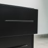 Close-up view of a modern black pedestal showing two drawers with sleek metal handles and a smooth matte finish.