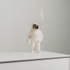 White 3 drawer chest of drawers with black handles and a small white astronaut figurine with a gold helmet displayed on top.