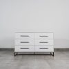 White six-drawer chest of drawers with black handles and steel base, ideal for modern bedroom or living room storage.