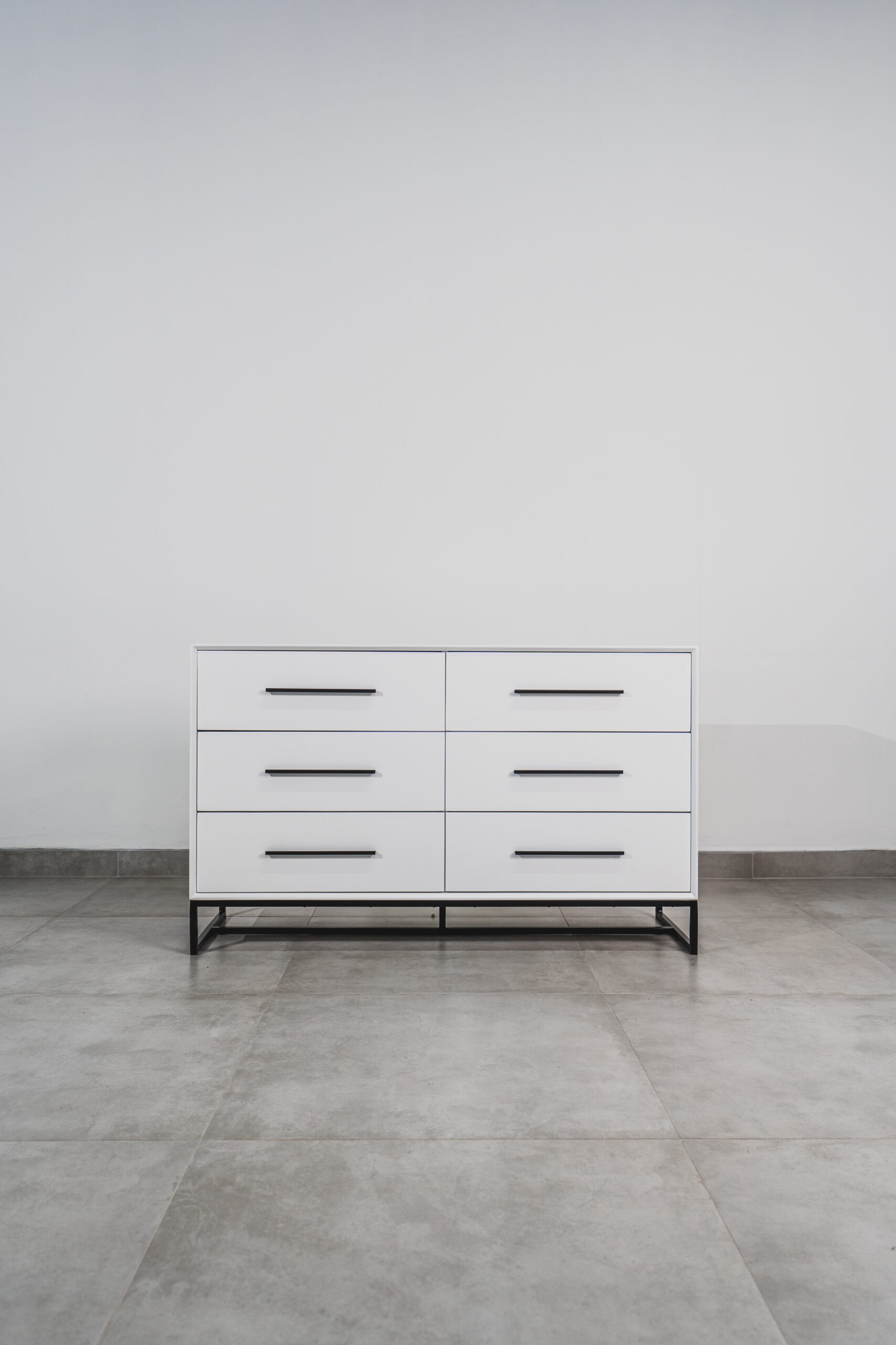 White six-drawer chest of drawers with black handles and steel base, ideal for modern bedroom or living room storage.