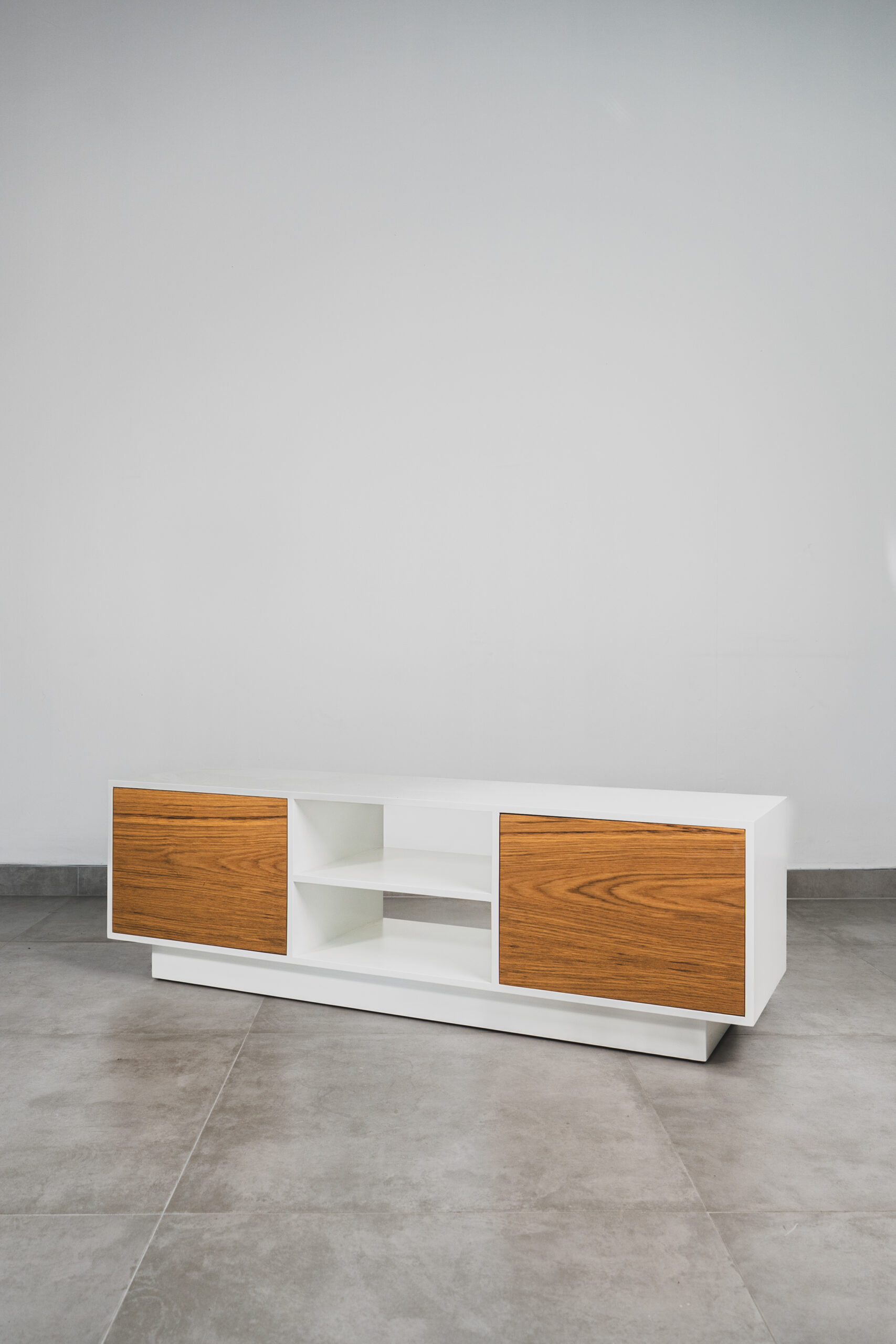 Scandinavian white TV stand with natural wood doors, open centre shelves, and floating base for a modern minimalist living room.