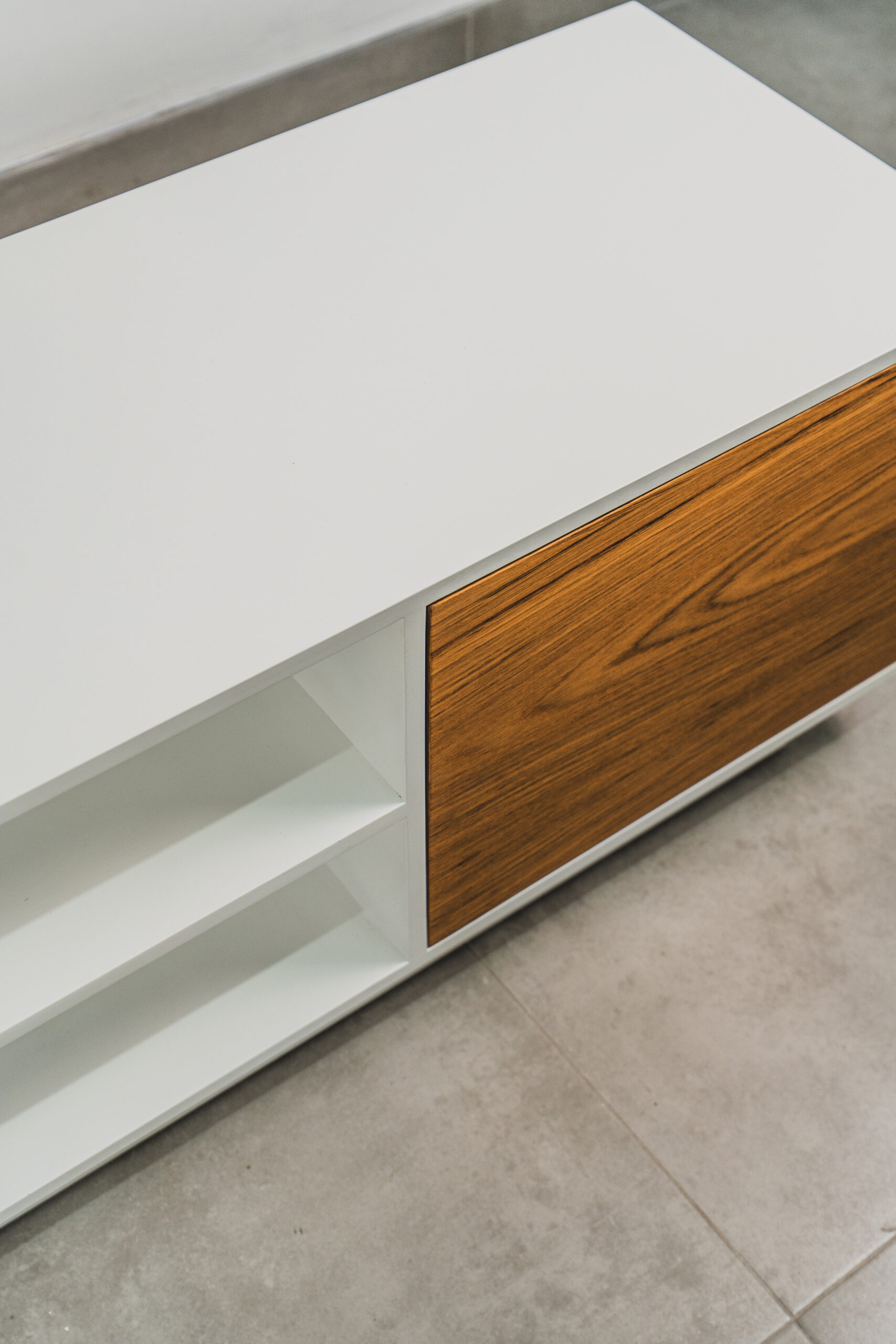 Close-up of a Scandinavian-style white TV stand with natural wood door and open shelving, showcasing minimalist craftsmanship and smooth finish.