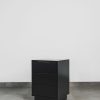 Modern black side table with three drawers and a sleek matte finish, ideal as a contemporary bedside pedestal.