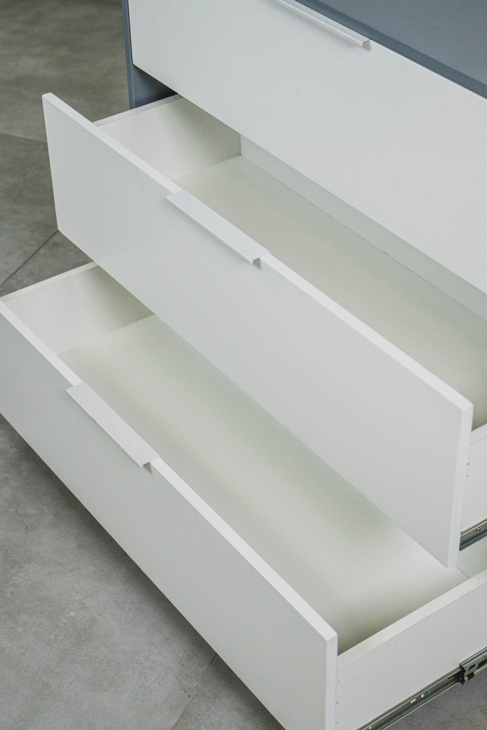 Close-up of a grey and white compactum showing two spacious white drawers fully open, highlighting the smooth interior and metal runner system.