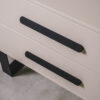 Detail view of a greige bedside table with two drawers, highlighting the clean finish and minimalist hardware.