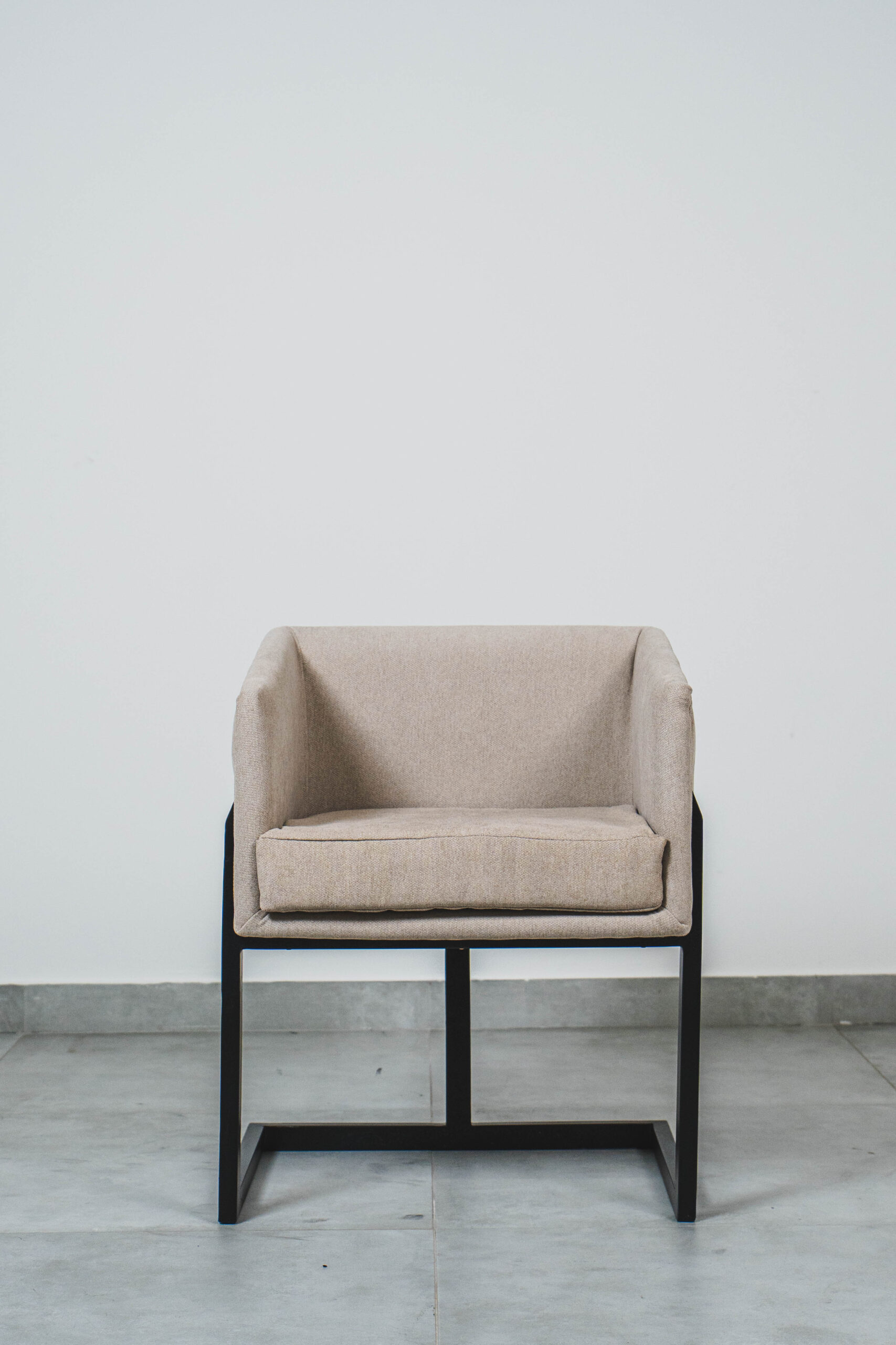Modern beige upholstered dining chair with a cushioned seat and black metal frame.